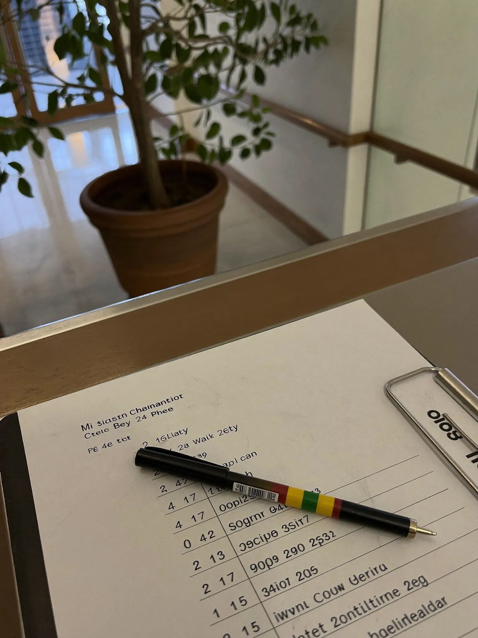 A facilities maintenance checklist on a clipboard with a pen on a clean reception counter in a bright corporate lobby
