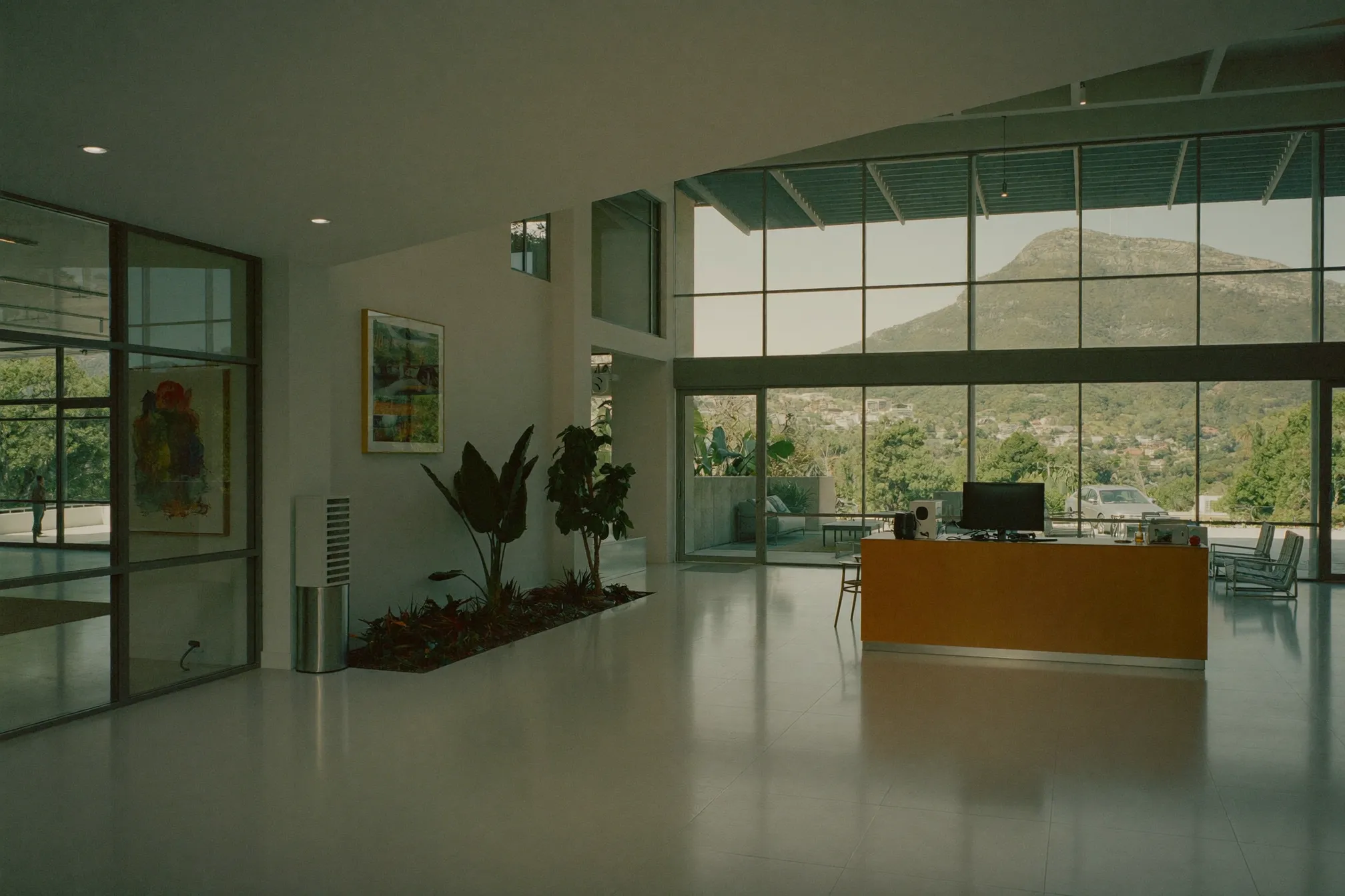 A bright, clean commercial building lobby in Cape Town with polished floors, a glass facade and indoor plants, Table Mountain visible through the windows